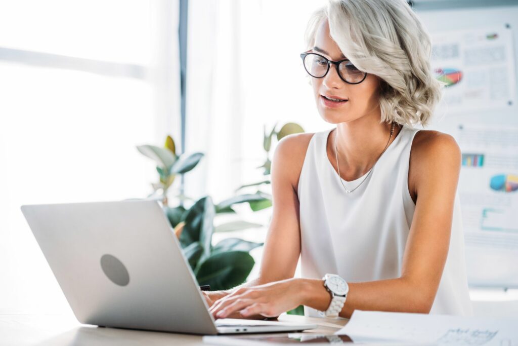 woman wearing white tank top working at a laptop