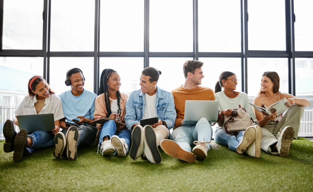 group of people sitting against a wall looking and smiling at one another