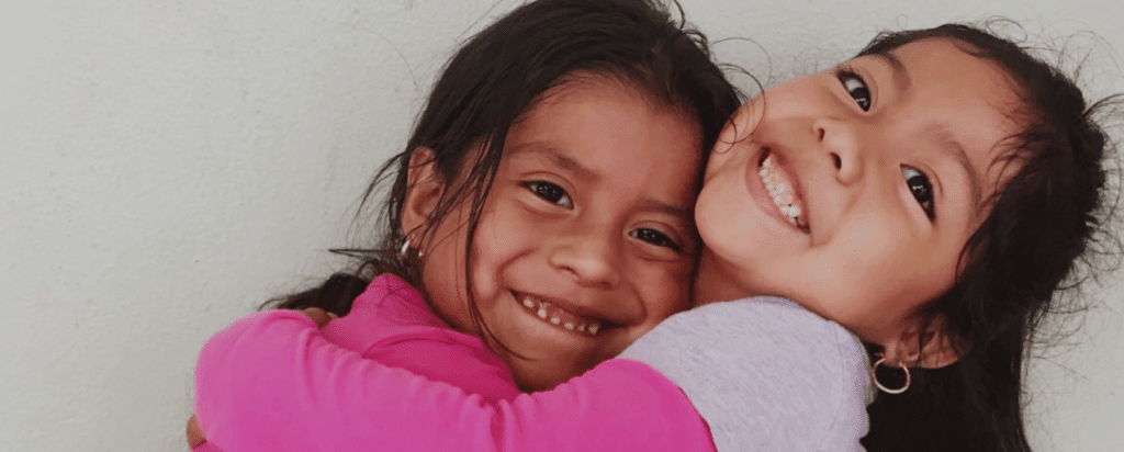 two little girls smiling and hugging