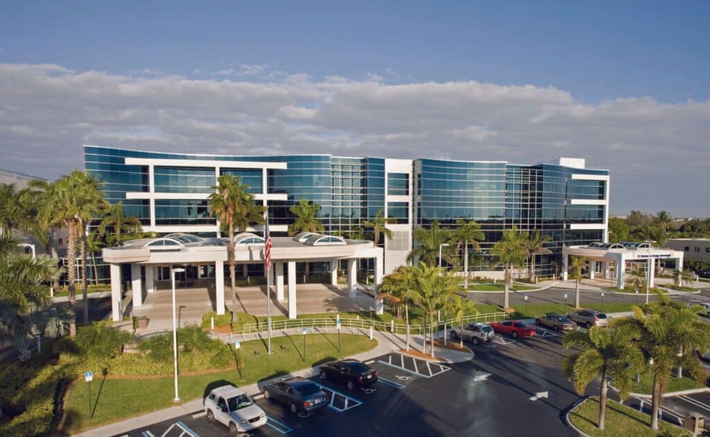 view of exterior of large glass building with parking lot