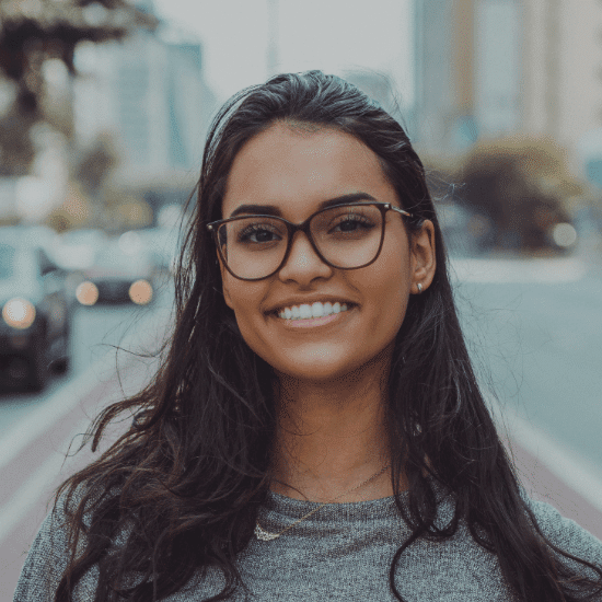 woman with glasses stands in street smiling