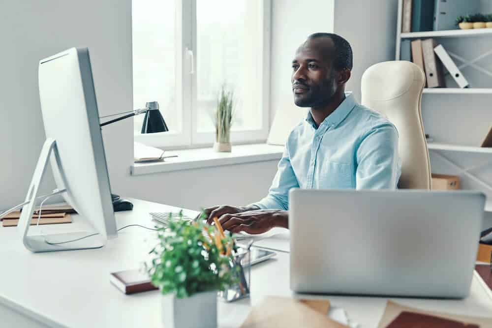 a business man wearing a blue shirt working at a desk looking at a computer