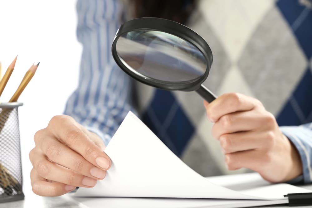 A person is holding a magnifying glass over a piece of paper