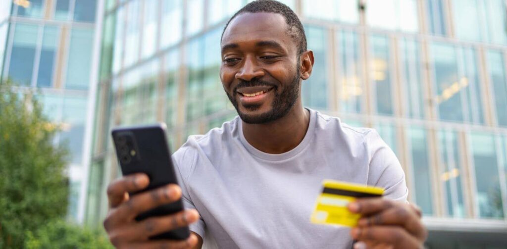 man wearing white shirt holding phone and credit card